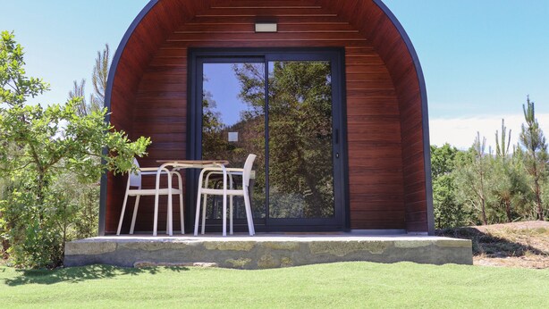 Il s'agit d'un bâtiment moderne doté d'une façade en bois aux lignes courbes et d'une porte en verre. Un petit espace extérieur aménagé avec deux chaises et une table invite à la détente.