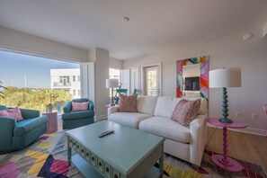 A modern living room with a white sofa, teal armchairs, and a coffee table.