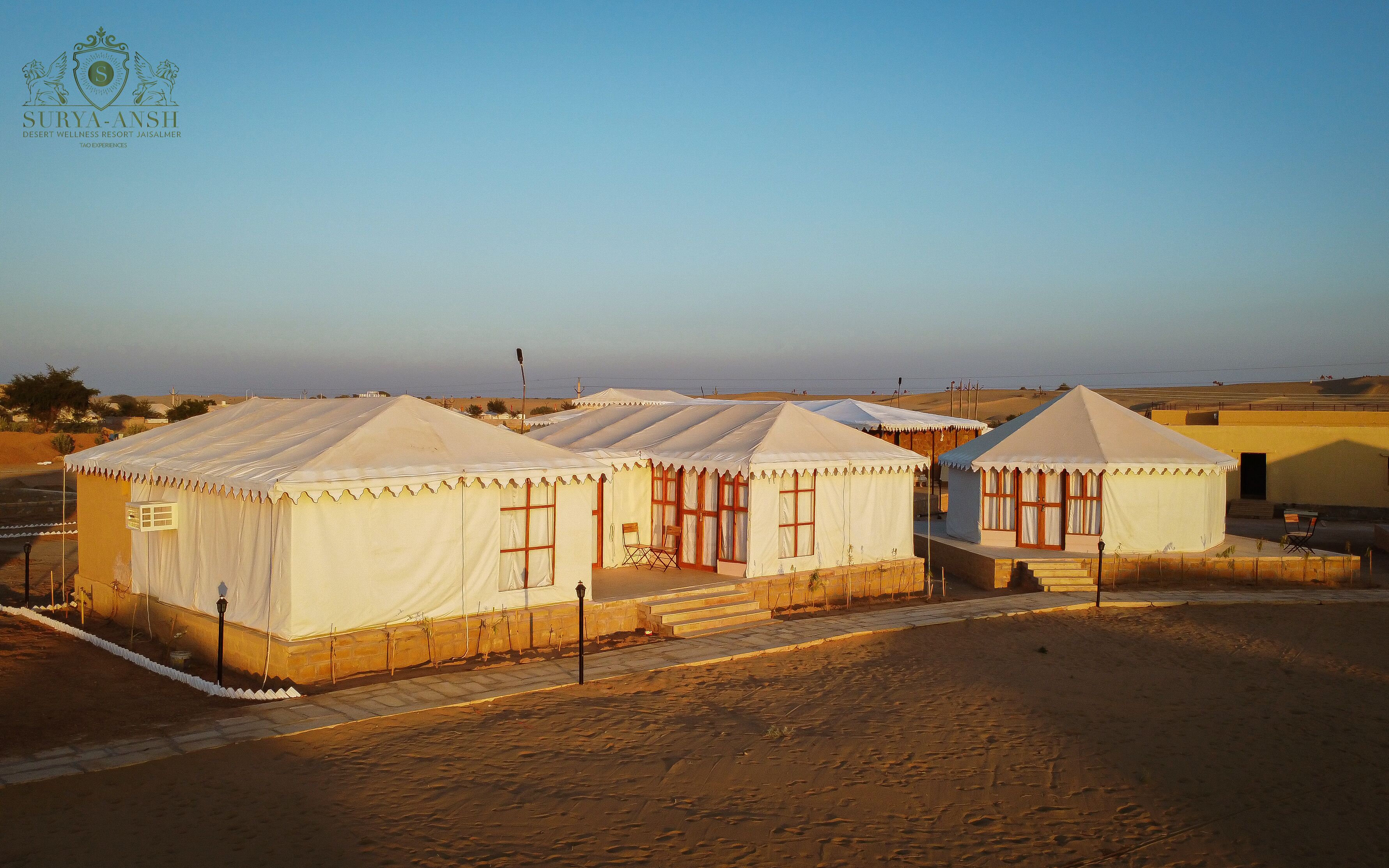 A desert wellness resort with multiple tents, each featuring a small porch and a window.
