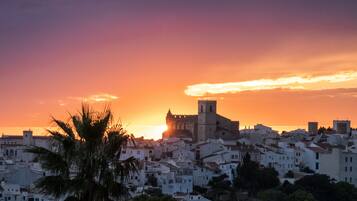 Un paisaje urbano costero al atardecer con un edificio histórico destacado y numerosos edificios blancos.