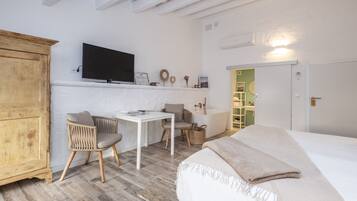 Un dormitorio con cama, escritorio, dos sillas, televisor y armario.