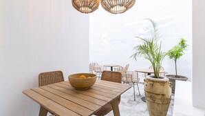 A wooden table with a bowl of fruit, wicker chairs, and hanging wicker light fixtures in a bright, open space with a view of the sky. - Encant de Alaior Boutique Hotel  (Alayor)