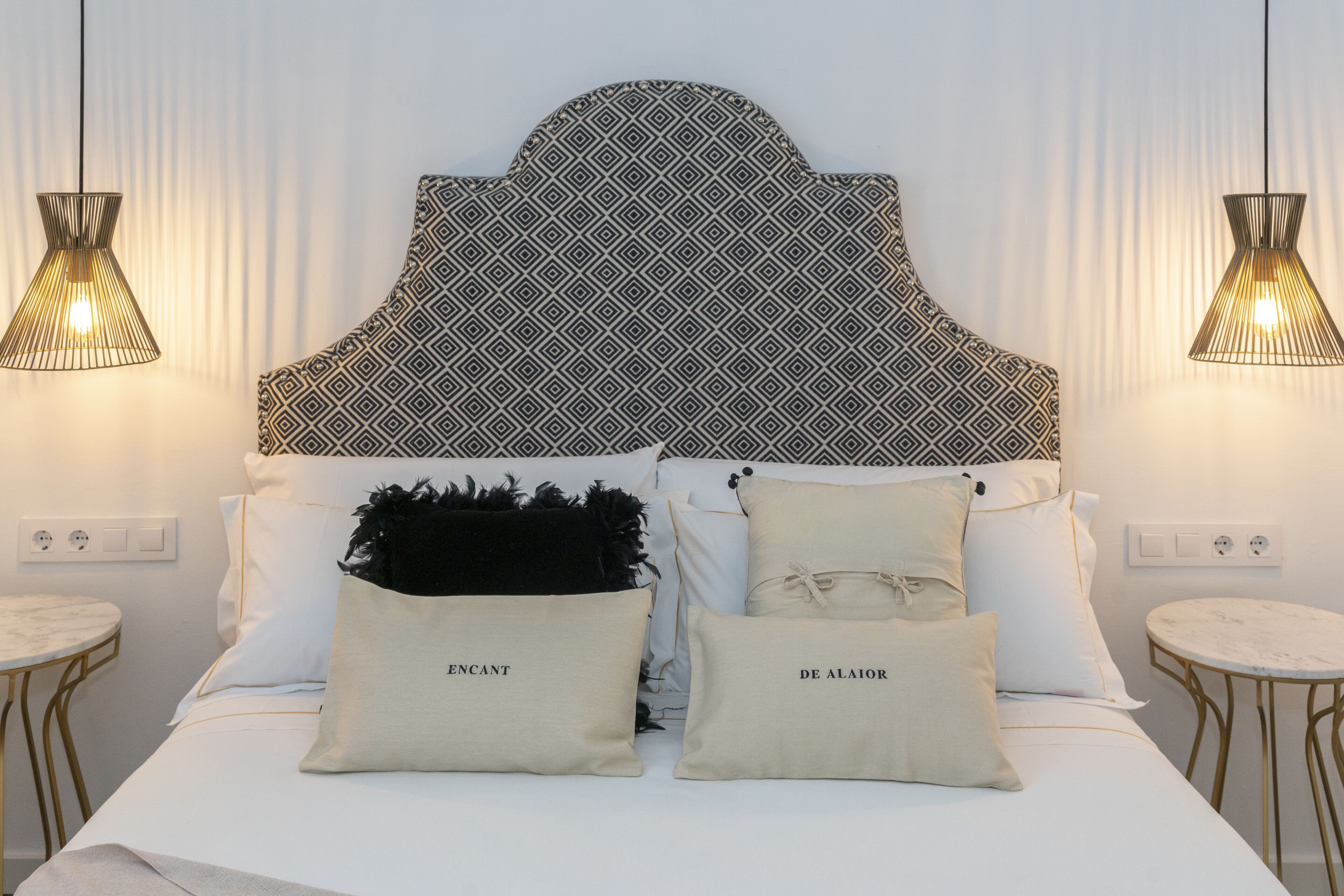 Un lit avec une tête de lit à motifs, deux tables de chevet et des lampes décoratives.
