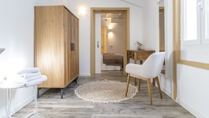 A hallway with a wooden wardrobe, a round woven rug, and a white chair. - Encant de Alaior Boutique Hotel  (Alayor)