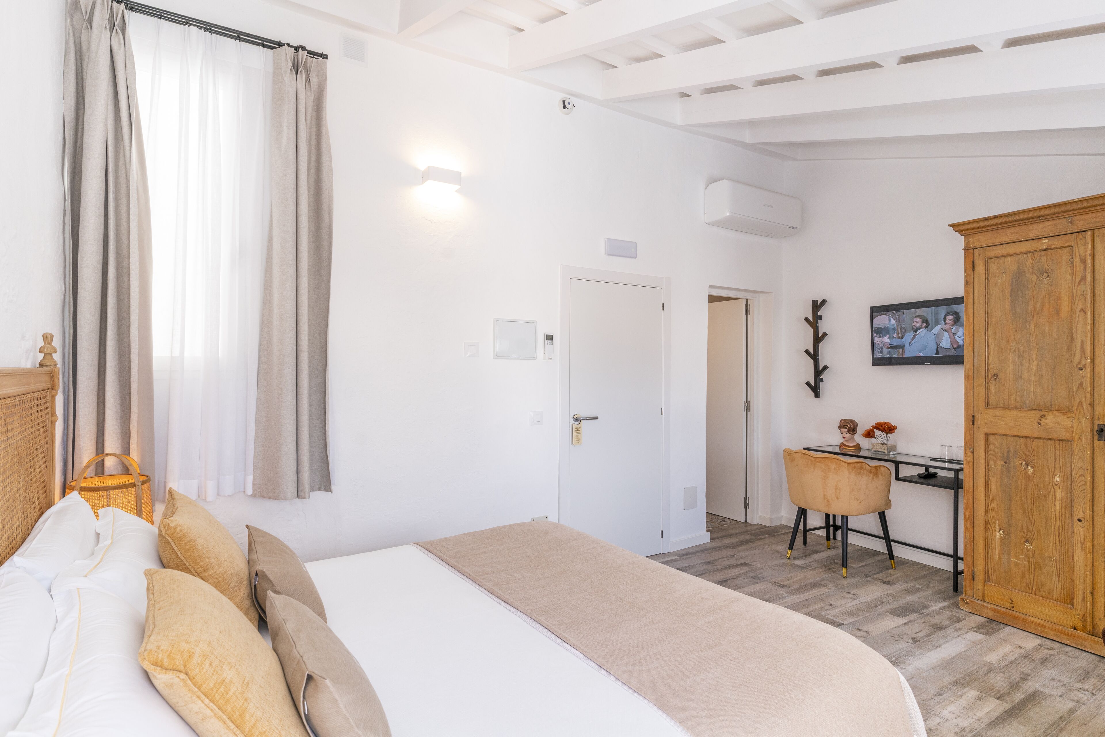 A bedroom with a bed, curtains, a desk, a chair, and a wardrobe.