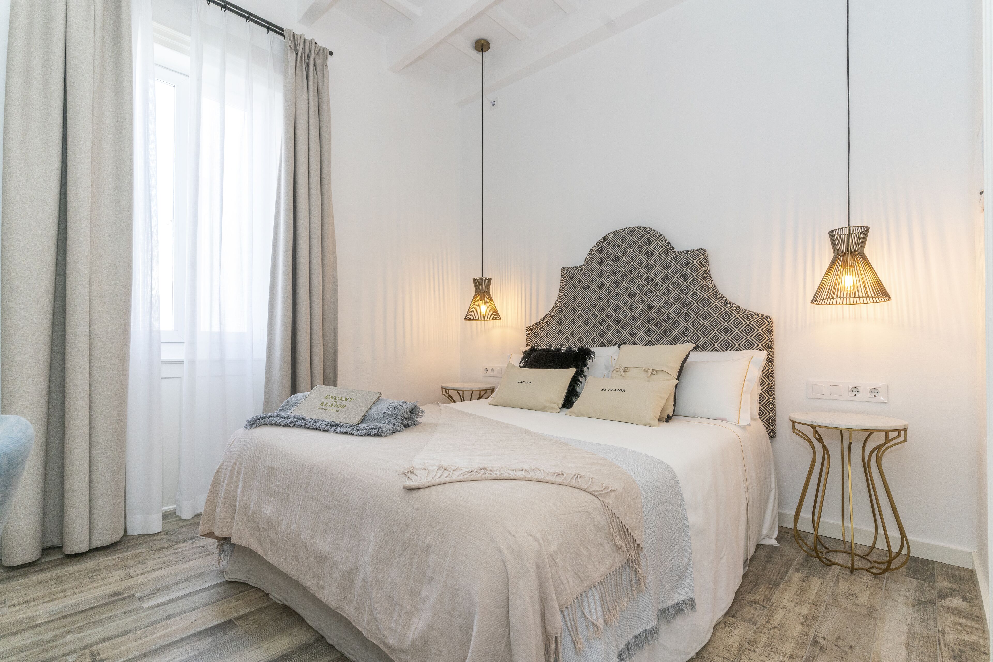 A neatly arranged bedroom with a large bed, two bedside tables, and a small side table.