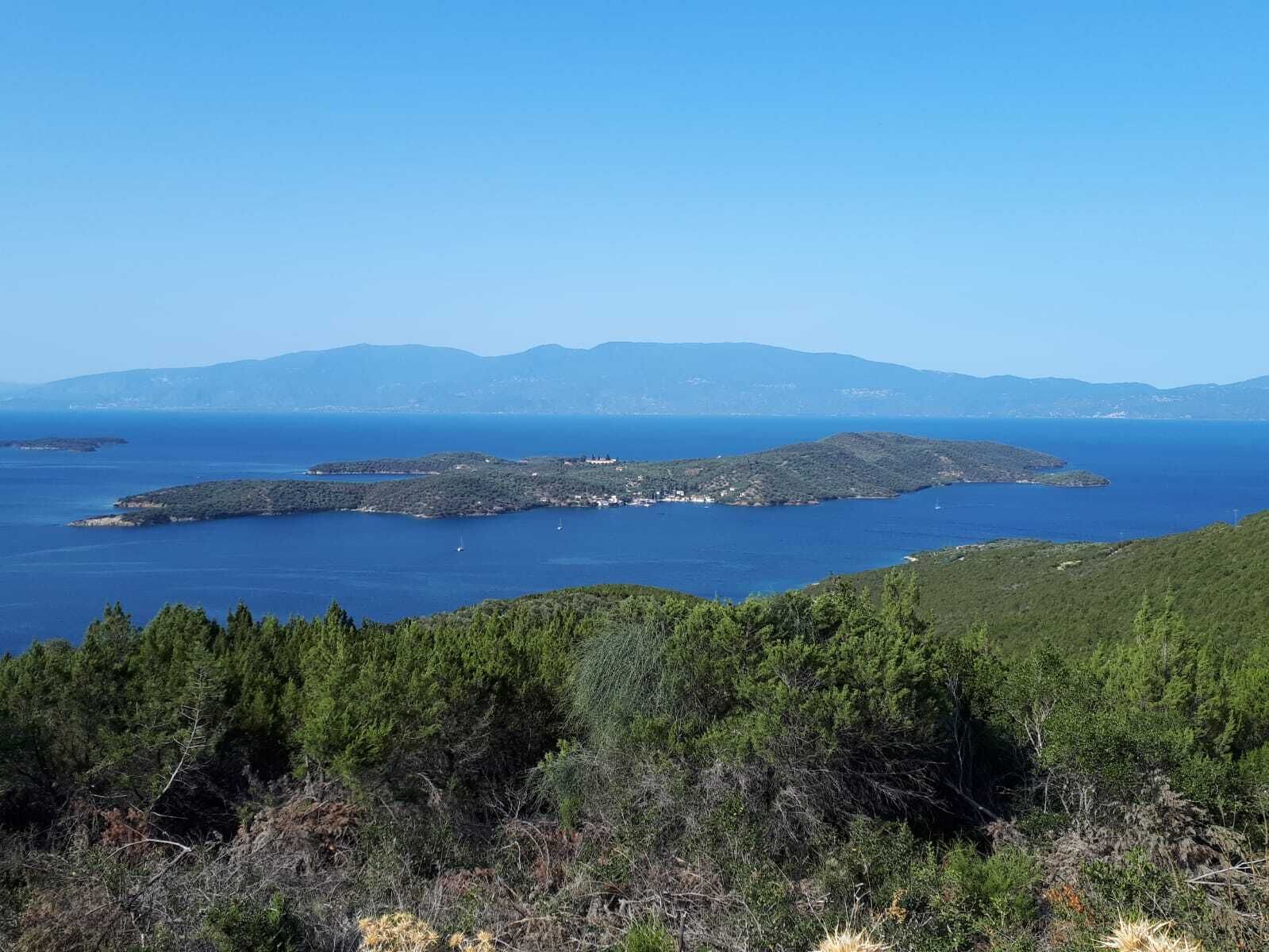 Un paysage côtier avec une petite île, une végétation luxuriante et une mer d’un bleu limpide.