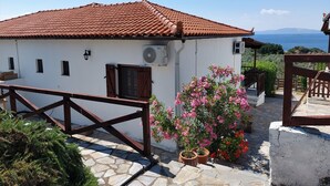Un bâtiment blanc avec un toit recouvert de tuiles rouges, une porte en bois et des plantes en pot.