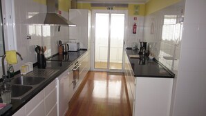 Een keuken met witte kasten, roestvrijstalen apparatuur en een houten vloer.