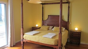 Een hemelbed met een baldakijn, twee nachtkastjes en een raam met gordijnen.