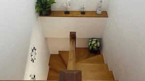 A wooden staircase with a shelf above it holding decorative items. - LAUNCHED HOLIDAYS (Sanxenxo)
