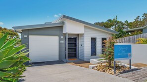 A modern two-story house with a garage, a covered entryway, and a well-maintained garden.