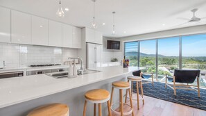 A modern kitchen with a large island, bar stools, and a view of the outdoors.