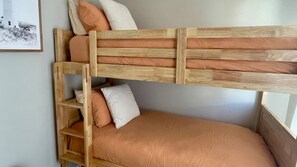 A bunk bed with a wooden frame and orange bedding.