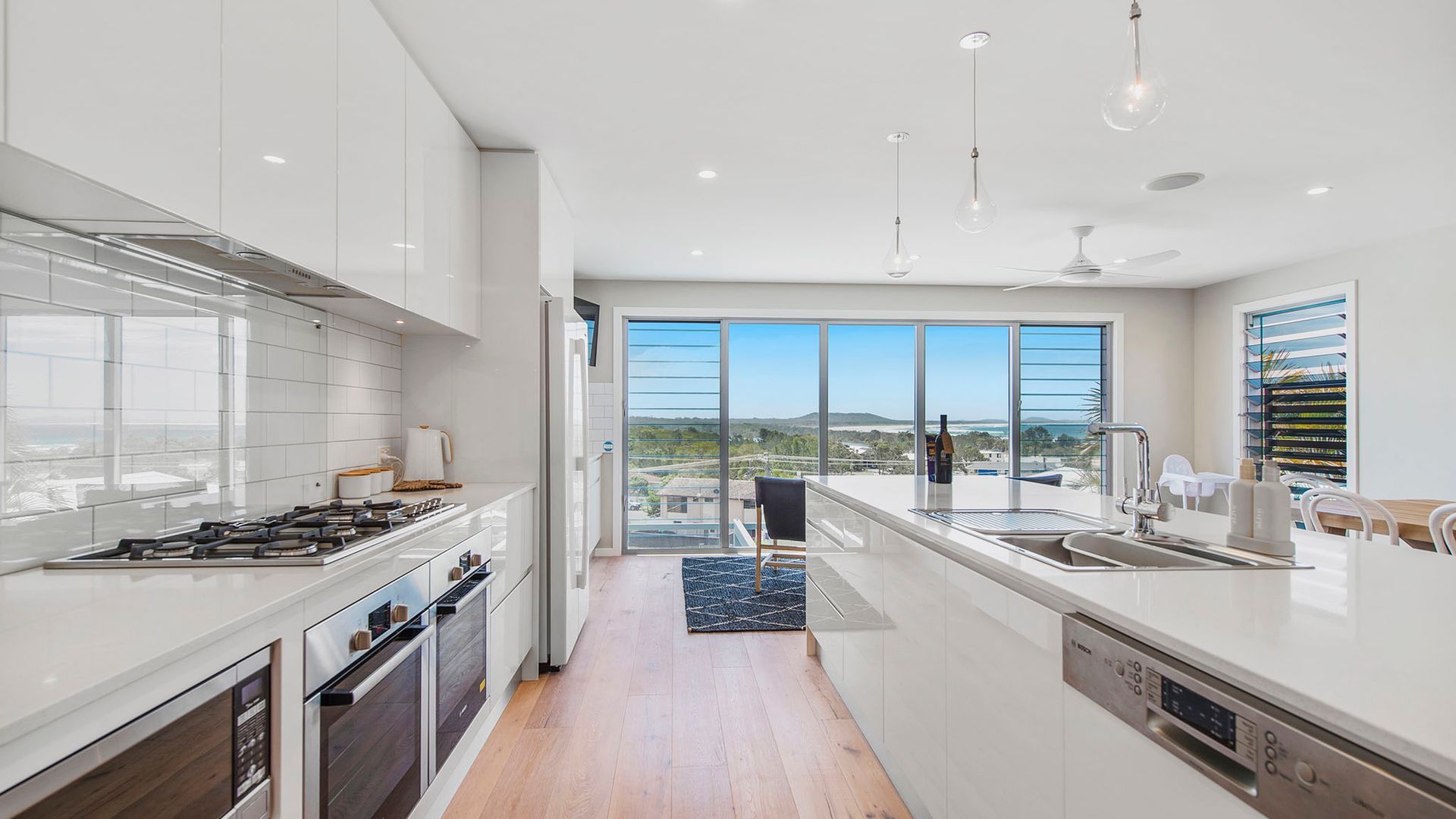A modern kitchen with a view of the landscape, a dining area with a view, and a large window.