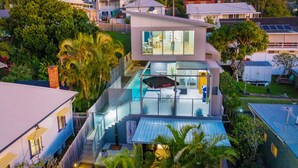 Et moderne hus med en glasindkapslet terrasse, en swimmingpool og et parabolantenne.