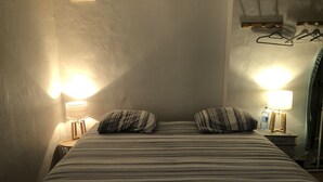 Une chambre d’hôtel avec un lit, deux oreillers, deux lampes de chevet et une bouteille d’eau sur une table de chevet.