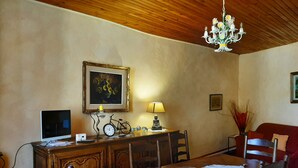 Un coin repas comprenant une table en bois, des chaises, un lustre, un tableau et une lampe.