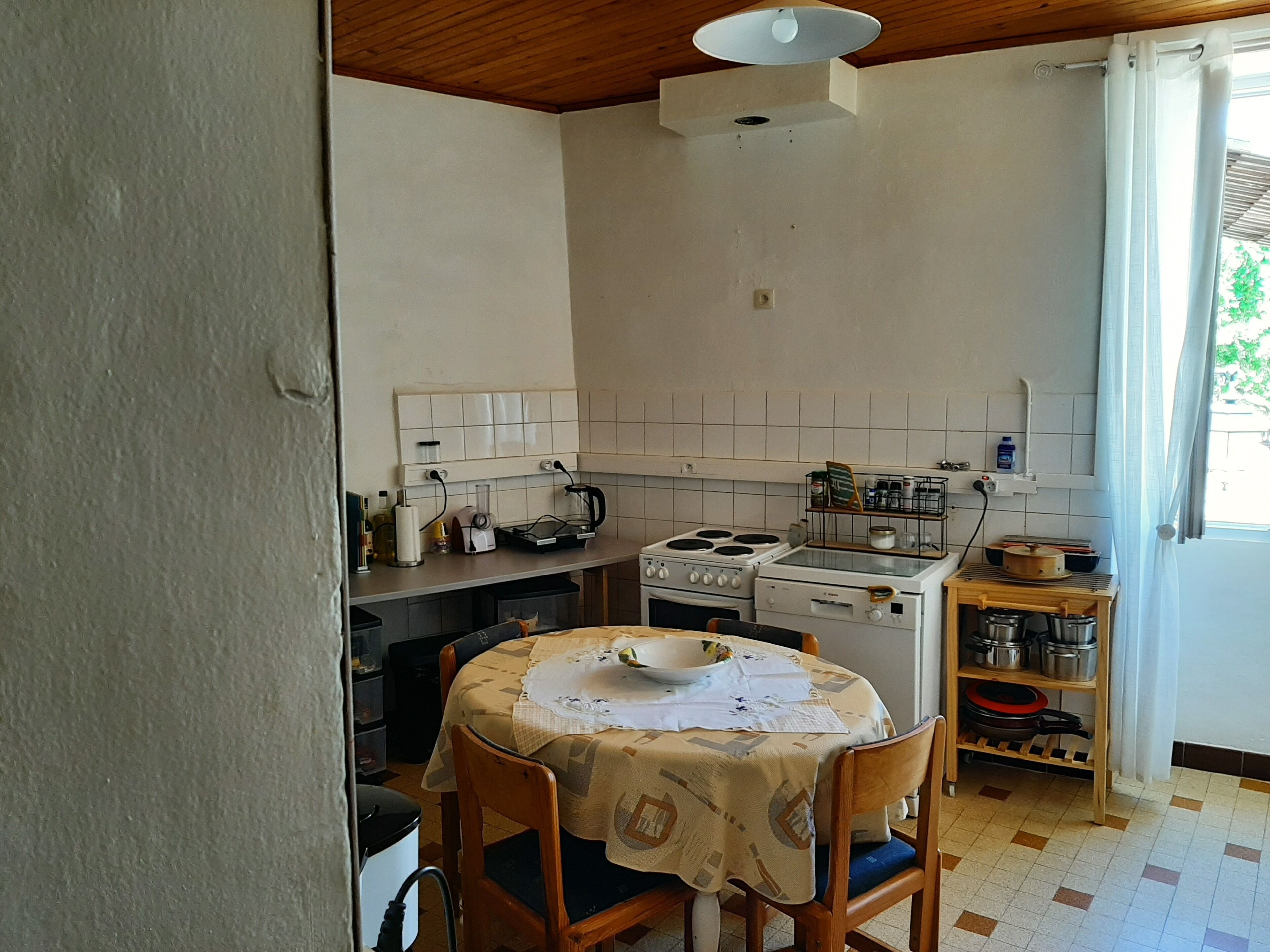 Een kleine keuken met een eettafel, stoelen, een fornuis en een spoelbak.