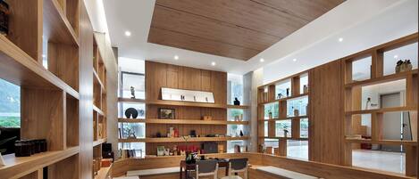 A modern interior with wooden shelving, a seating area, and a view through large windows.
