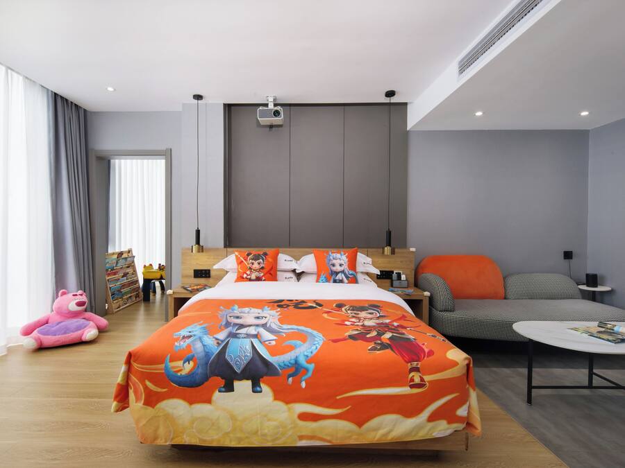 Quarto de hotel moderno com cama, sofá, mesa de centro e uma janela grande.
