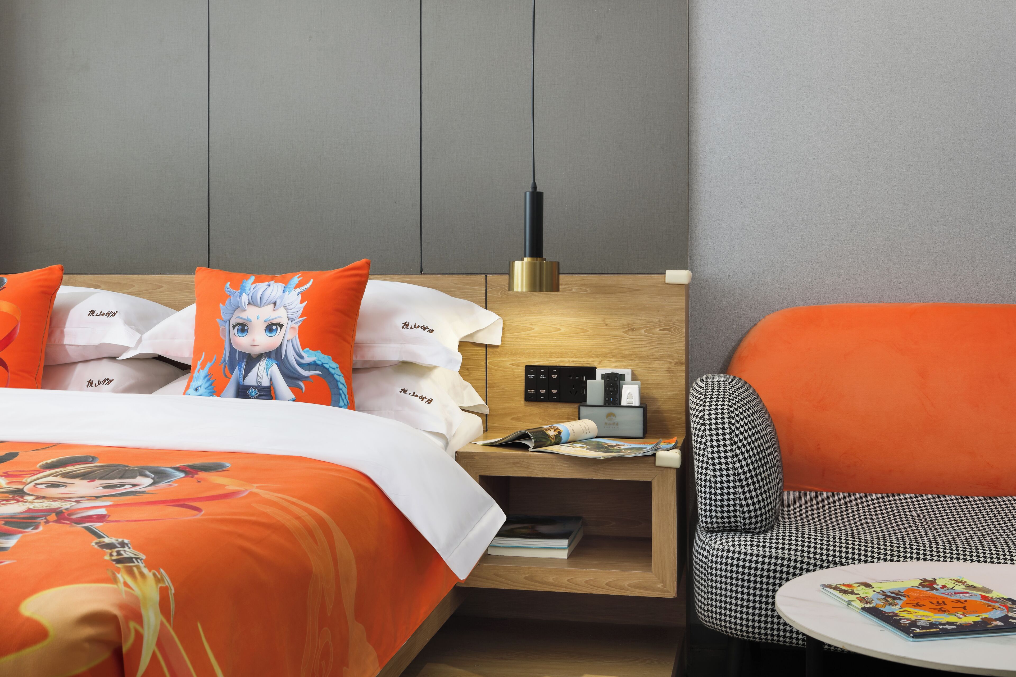 Et hotelværelse med en seng, et sengebord med lampe, en stol og et lille bord med et magasin.
