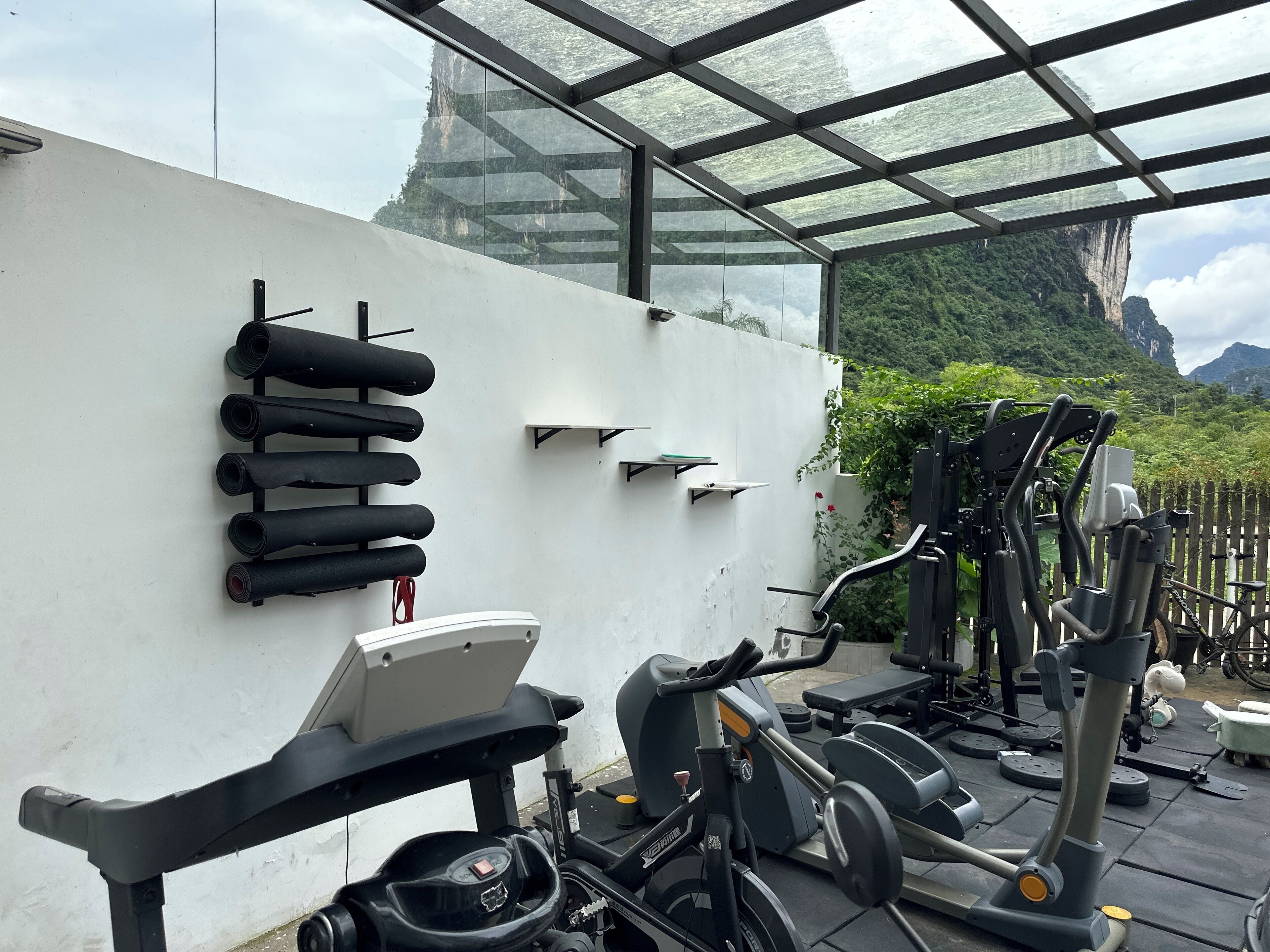 A gym with exercise equipment, including a stationary bike, elliptical, and weights.