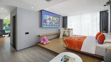 Una habitación de hotel moderna con una cama, un televisor montado en la pared, un escritorio pequeño y una ventana con cortinas.
