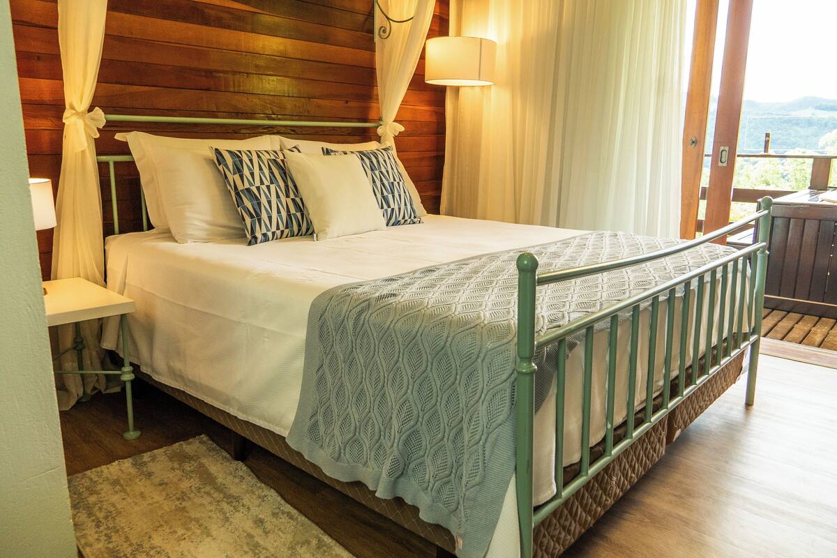 A bed with a canopy, pillows, and a bedside table.