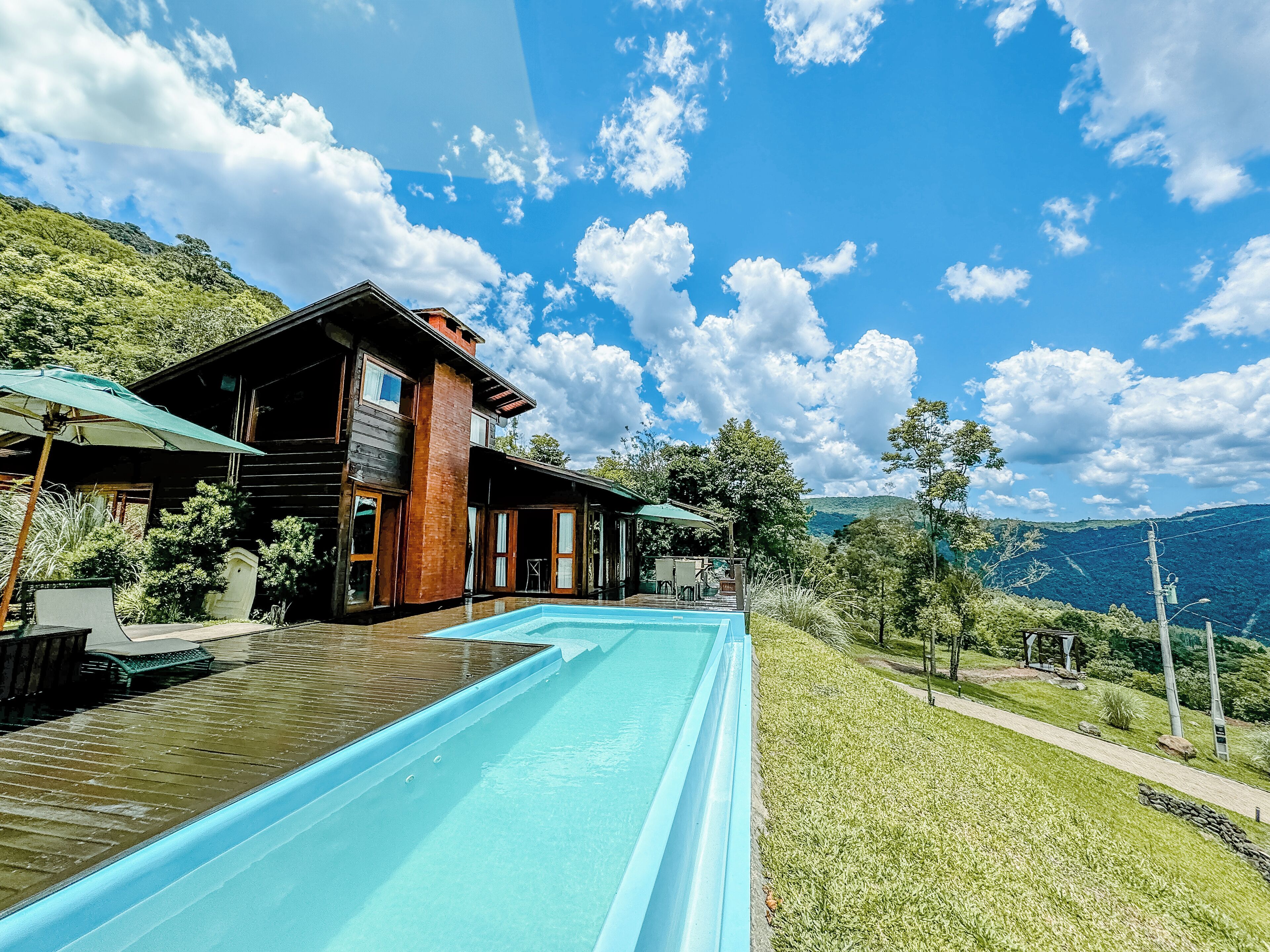 Uma casa moderna com piscina, deck de madeira e vista para as montanhas.