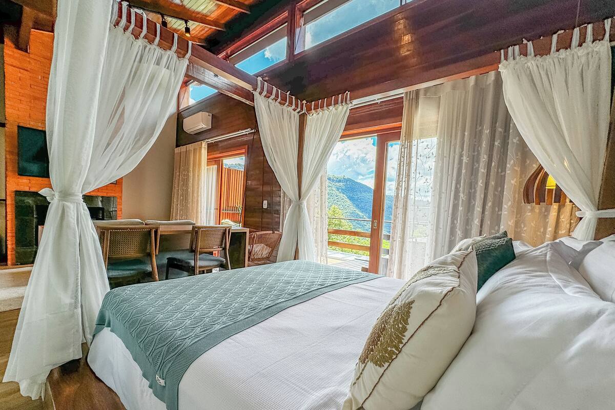 A bedroom with a bed, a desk, and a view of the outdoors.