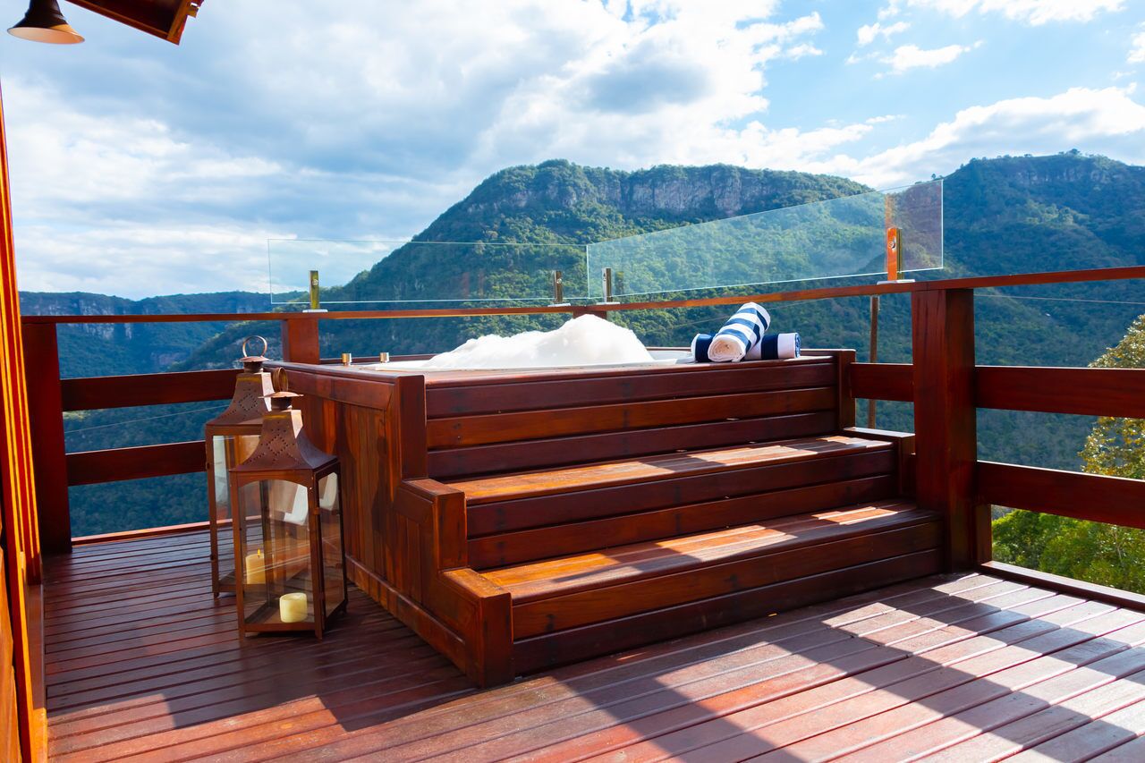 A wooden deck with a bench and lanterns, overlooking a mountainous landscape.