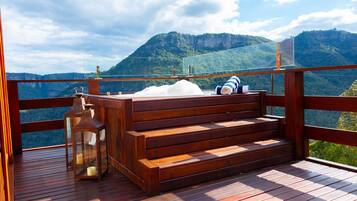 A wooden deck with a bench and lanterns, overlooking a mountainous landscape.