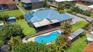Une propriété résidentielle dotée d’une piscine, de panneaux solaires et d’un espace extérieur couvert.
