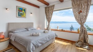 A bedroom with a bed, a window with curtains, a painting on the wall, and a view of the sea. - Villa Karla, pool with beautiful sea view (Opatija)