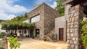 A stone building with a large window, a staircase, and potted plants. - Villa Karla, pool with beautiful sea view (Opatija)