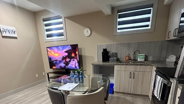 Un espacio habitable compacto con comedor, kitchenette y televisor mostrando una escena de atardecer.