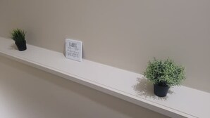 Una estantería blanca con dos plantas en macetas y un cartel.