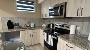 Una cocina moderna con armarios de madera clara, electrodomésticos de acero inoxidable y encimera de granito.