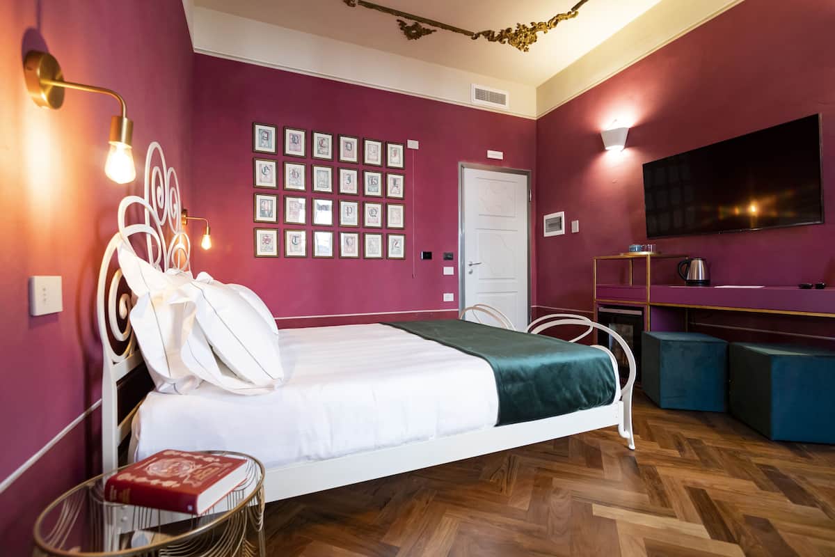 A bedroom with a bed, bedside table, wall-mounted TV, and framed pictures.