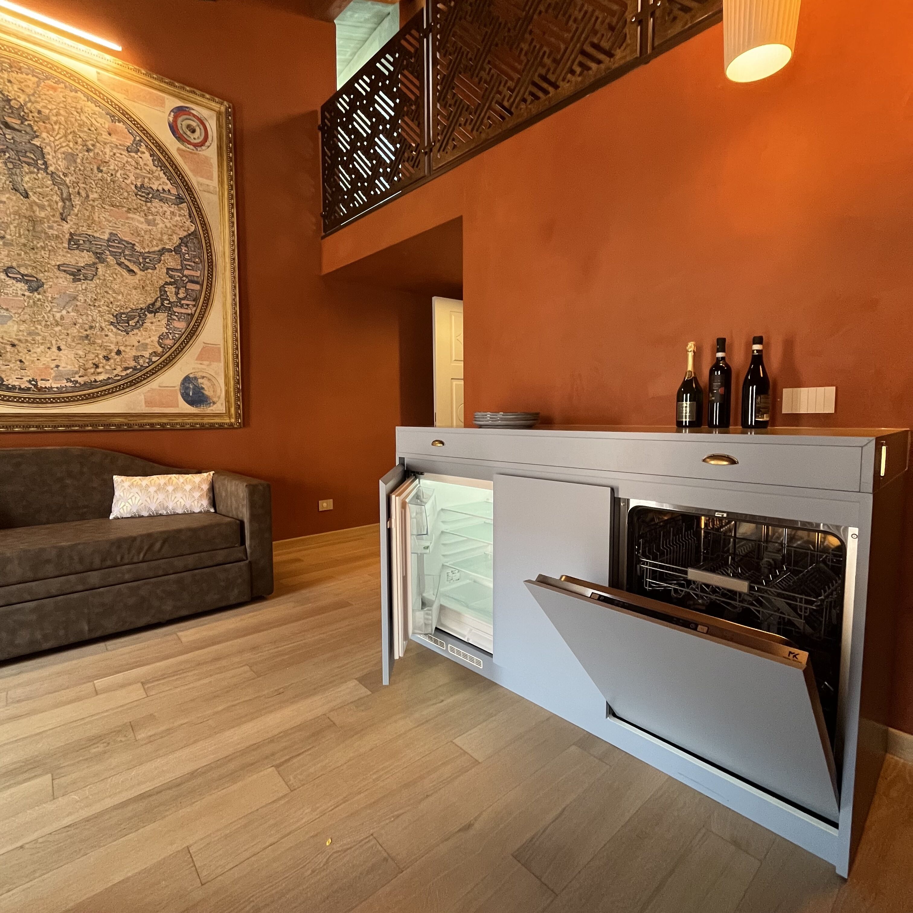 Une cuisine moderne dotée d’un four encastré, d’un plan de travail gris et d’un élément décoratif mural.