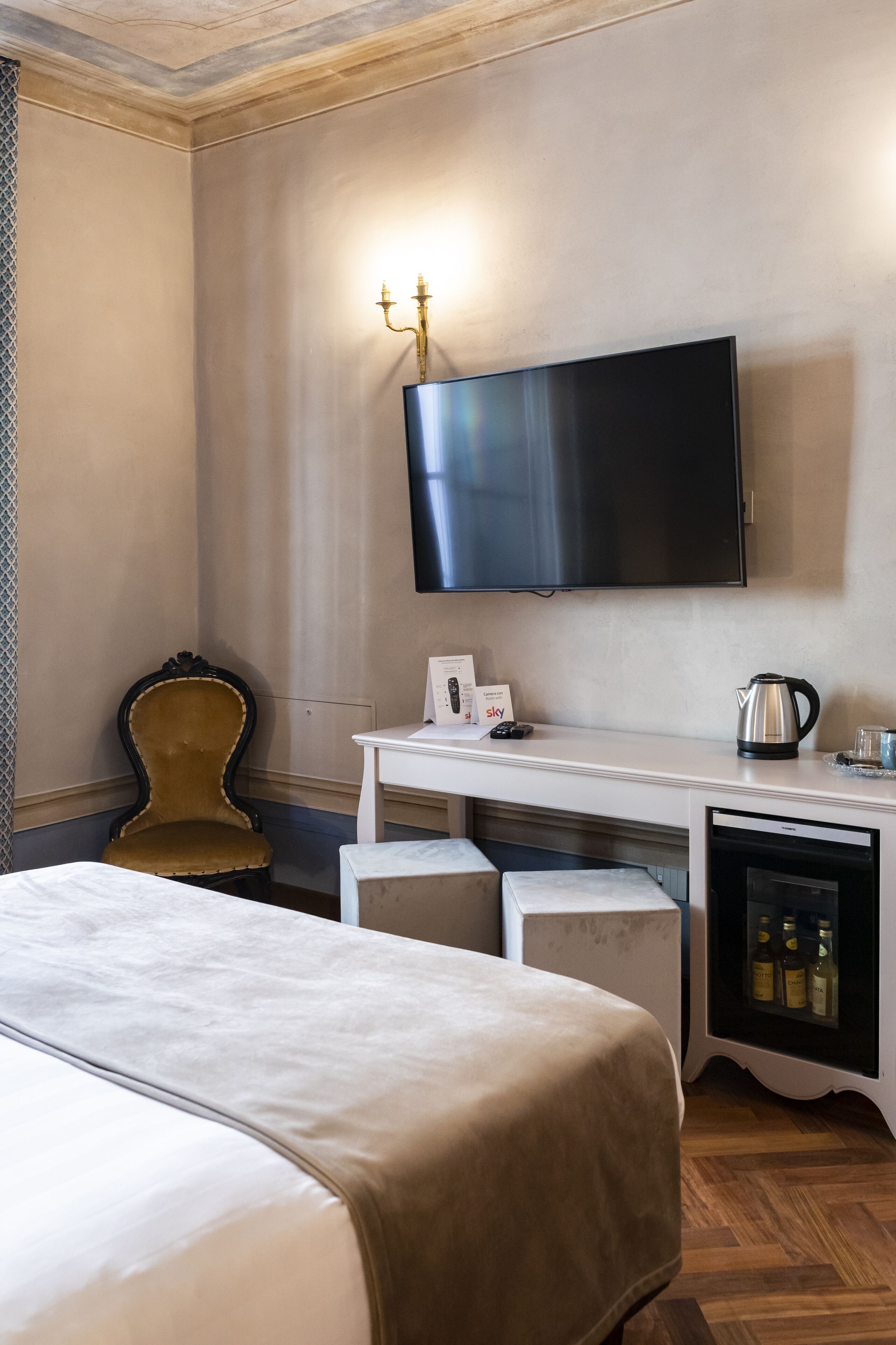 A hotel room with a bed, a desk, a television, a coffee maker, and a minibar.