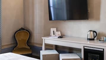 A hotel room with a bed, a desk, a television, a coffee maker, and a minibar.