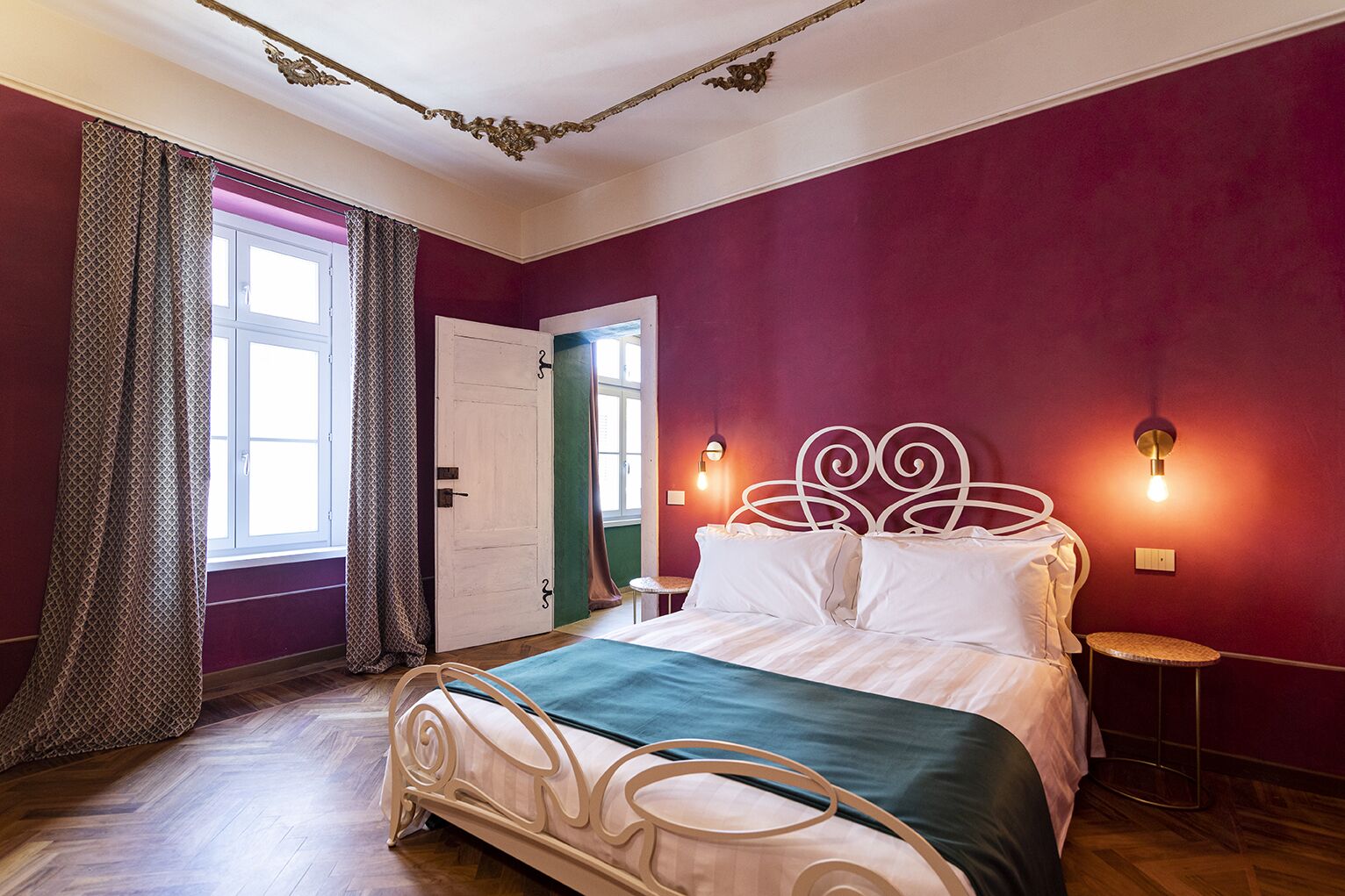 Une chambre à coucher avec un lit, des rideaux, une porte et des lampes fixées au mur.