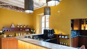 A modern kitchen with a central island, wooden cabinets, and a built-in wine cooler. - Palazzo Fauzone Relais (Mondovi)