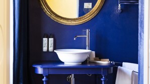 A bathroom with a white sink, a gold-framed mirror, and a blue vanity. - Palazzo Fauzone Relais (Mondovi)