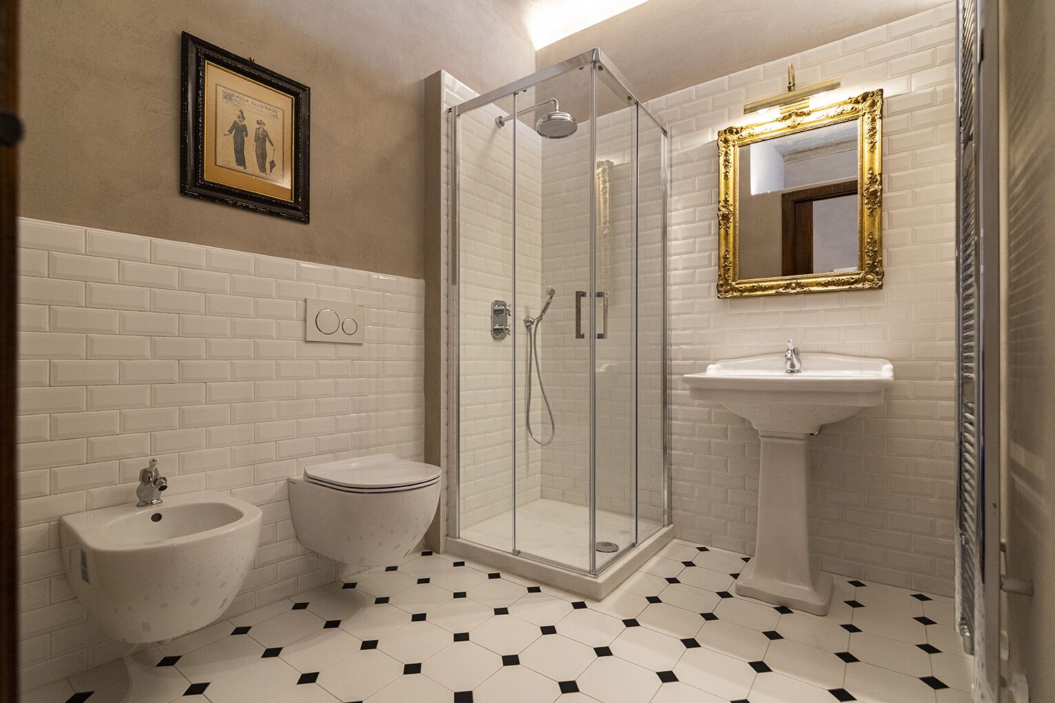 A bathroom with a glass-enclosed shower, a pedestal sink, and a bidet.