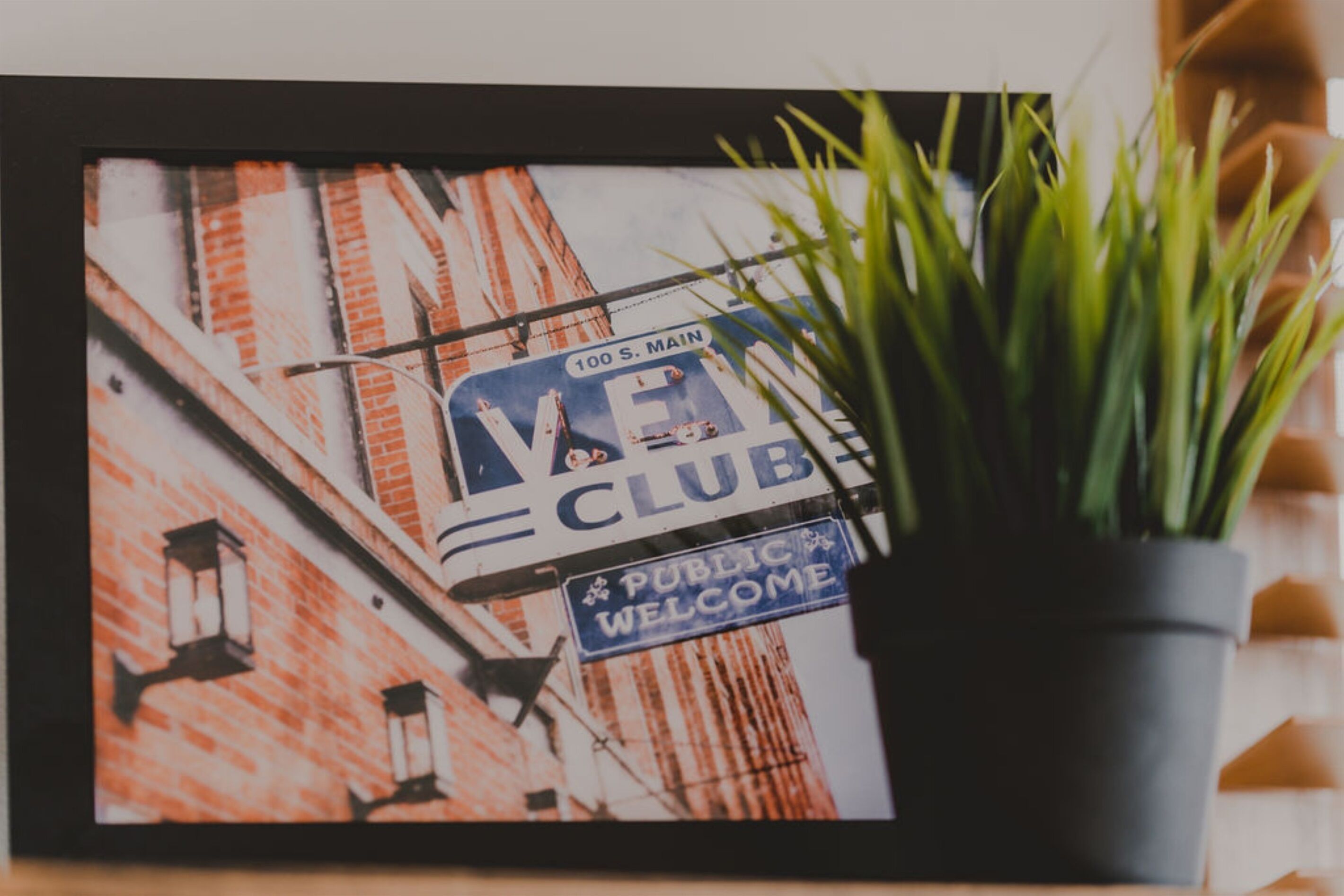 A framed photograph of a building with a 'Vegan Club' sign and a 'Public Welcome' sign.