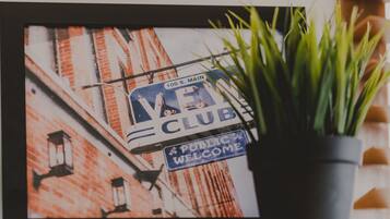 A framed photograph of a building with a 'Vegan Club' sign and a 'Public Welcome' sign.
