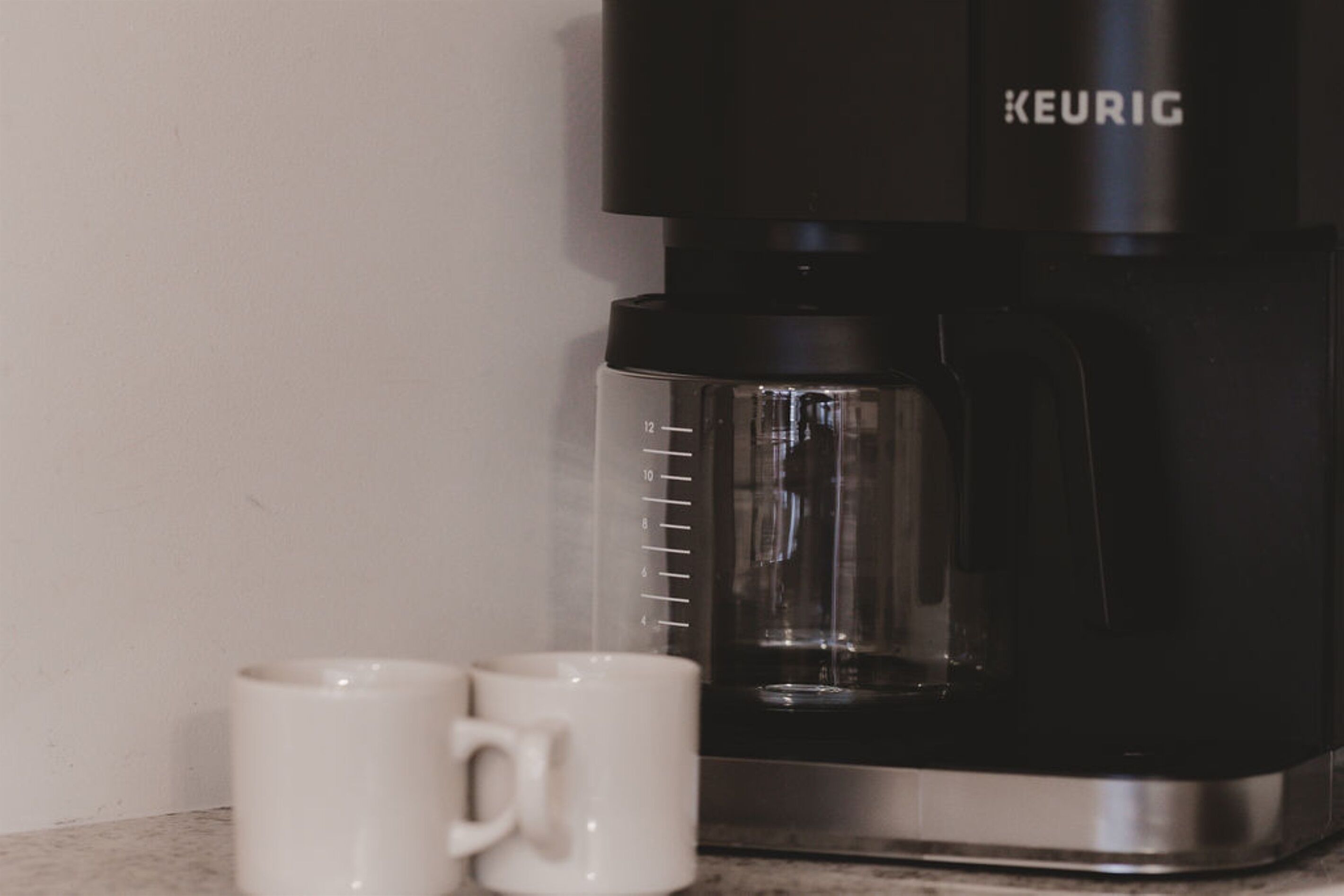 Una cafetera Keurig con jarra y taza medidora.